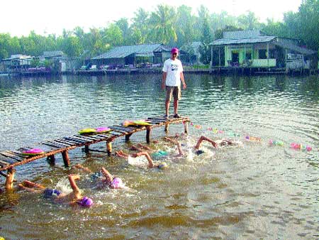 In at the deep end: Nguyen Quoc Phi stands on the bridge over the Xeo Ro Canal observing and instructing the local children how to swim every afternoon after school. In at the deep end: Nguyen Quoc Phi stands on the bridge over the Xeo Ro Canal observing and instructing the local children how to swim every afternoon after school.