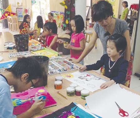 Colourful treatment: Tham Cam Phuong, the owner of the Pallet workshop, helps children to paint. Colourful treatment: Tham Cam Phuong, the owner of the Pallet workshop, helps children to paint.